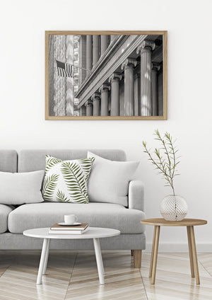 An American flag projects from a historic New York building beside tall stone columns.