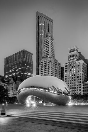 Cloud Gate’s polished curved surface mirrors Chicago architecture above illuminated park paving.