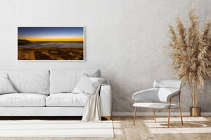 Wide coastal photograph of Clovelly Beach with textured foreground rock and soft dawn colour.