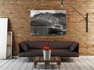 Fog drifts above forest and exposed mountain rock behind a quiet coastal boat.