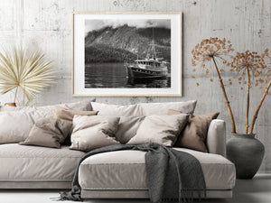 Horizontal British Columbia photograph showing a boat, calm reflections and misty mountain scenery.