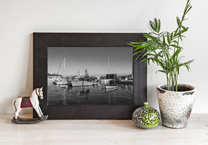 A small foreground sailboat rests before larger vessels along the Irish waterfront.