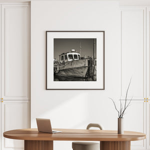 The bow of a weathered boat reflects in rippling water beneath its small wheelhouse.