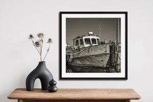 Square black and white photograph of an old Cobh fishing boat with textured wooden planks.
