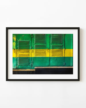 Green train shutters crossed by a bright yellow stripe in Coonoor, India.