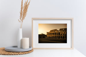 A broad golden sky frames the weathered exterior of Rome’s Colosseum at dusk.