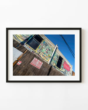Colourful cartoon mural across a Dallas building photographed beneath a clear blue sky.