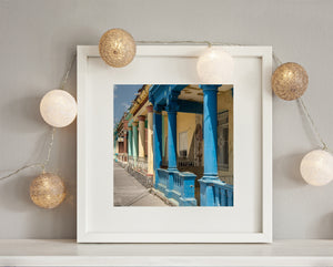 Sunlight highlights decorative columns and iron railings along Cuban houses.