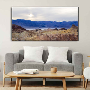 Clouded light reveals subtle cream, brown and rose tones across folded desert terrain.