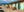 A long row of pastel Cuban houses with blue doors borders a sunlit cobblestone street.