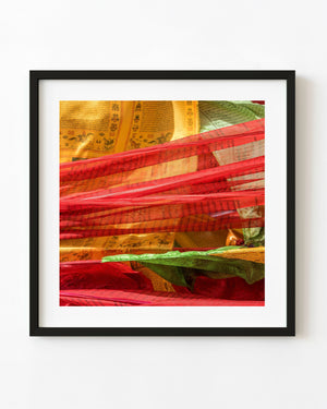 Close-up photograph of red, gold and green Tibetan prayer flags with printed markings.