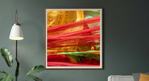 Warm golden cloth and translucent red bands overlap across a close view of prayer flags.