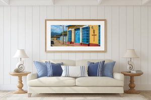 Colourful Trinidad architecture stretches toward distant mountains beneath a cloudy blue sky.
