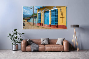 Blue doors and windows stand above a red base along a yellow Cuban building.