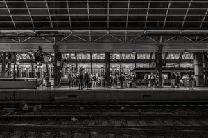 People standing on railway platform under steel roof Amsterdam station
