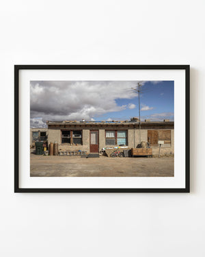 A weathered former gas station converted into a home beneath a dramatic Arizona sky.