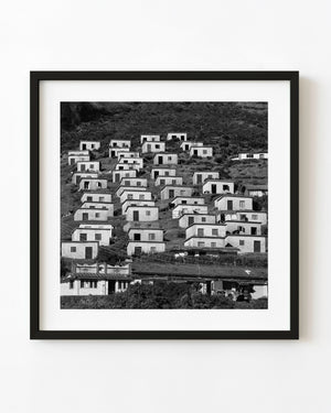 Black and white photograph of rows of pale hillside houses in Coonoor, India.