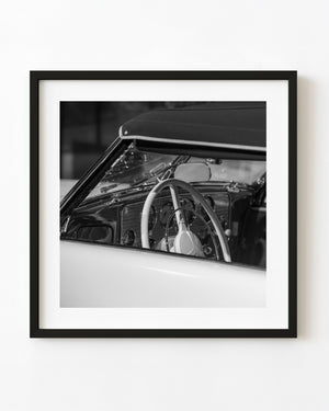 Black and white photograph of a Cord roadster interior with a pale steering wheel.