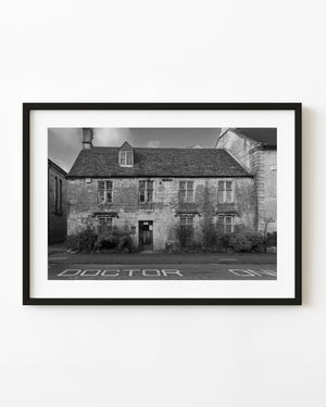 Black and white photograph of a stone doctor’s office building in the Cotswolds, England.