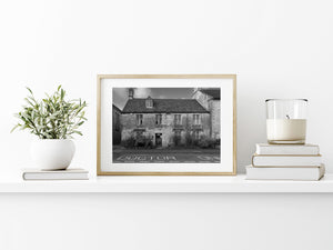 A doctor’s office occupies a weathered Cotswolds building with plants along its lower walls.