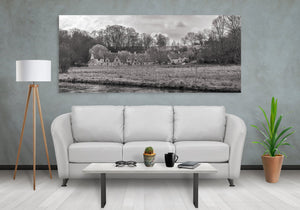 Monochrome rural landscape showing Cotswolds houses nestled among bare-branched trees.