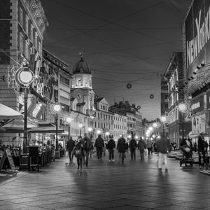 Zagreb city street at night with pedestrians walking under street lights