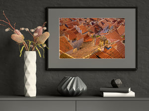 Weathered chimneys rise among tightly clustered red and orange tiled roofs.