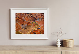 A Croatian city rooftop scene combines warm roof tiles with irregular stone structures.