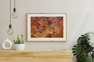 Terracotta roof surfaces intersect around pale chimneys and small rooftop windows.