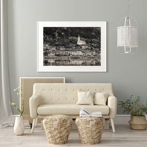 Black and white river village photograph connecting hillside buildings with their water reflections.