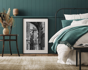 Bright buildings recede beyond a dark stone arch along a compact old town lane.