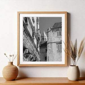 Square architectural photograph of weathered Croatian stonework and a bell tower rising between buildings.