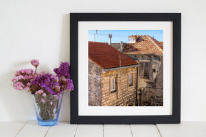 Angled tiled roofs meet above pale stone facades and dark window shutters.