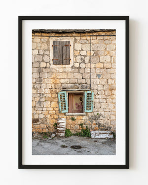 Turquoise shutters punctuate the weathered stone facade of an old Croatian house.