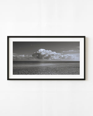 Bright clouds rise above an open Cuban ocean horizon in a panoramic black and white seascape.