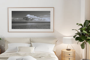 Wide ocean photograph of Cuba with layered cloud shapes and gently textured foreground water.