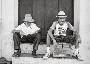 candid street portrait of Cuban men with cigars sitting outside doorway
