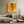 Looping wires and small electrical meters flank a wooden door on a sunlit yellow wall.