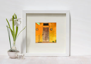 Worn vertical door boards form a dark rectangle against a richly coloured Cuban house wall.