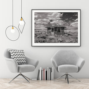 Black and white ghost town photograph of a weathered Nevada building beneath layered clouds.
