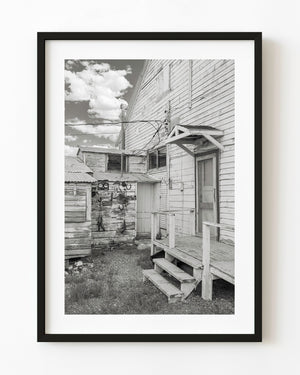 Wooden steps lead to the back door of an old store in Currie Nevada, photographed in black and white.