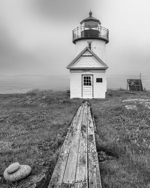 Faro blanco y negro con pasarela de madera en Maine