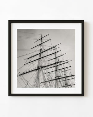 Cutty Sark masts and layered ropes rise against a pale sky in a toned monochrome nautical photograph.