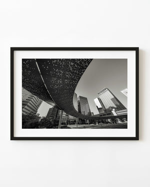 The curved Pacific Plaza pavilion sweeps above Dallas towers in a black and white architectural photograph.