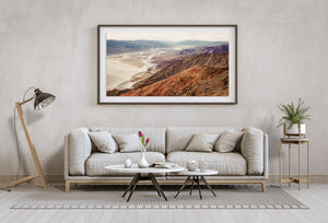 Pale irregular flats wind through Death Valley below rugged brown slopes and cooler distant peaks.