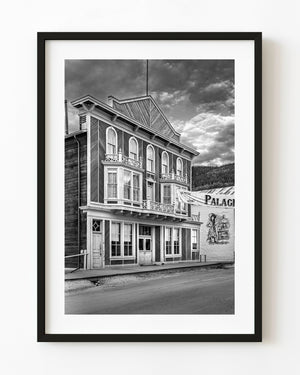 The Palace Grand Theatre in Dawson City stands beneath textured clouds in black and white.