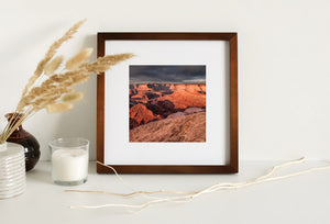 Dark storm clouds contrast with warm red and orange rock in the Dead Horse Point landscape.