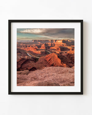 A winding river curves between warm red canyon walls below Dead Horse Point in Utah.