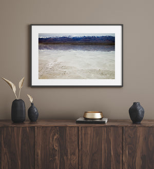 Death Valley landscape photograph of salt flats, calm reflections and a snow-lined mountain ridge.