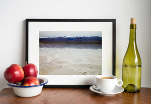 Delicate salt ridges and rough white ground contrast with the dark mountain horizon at Badwater Basin.